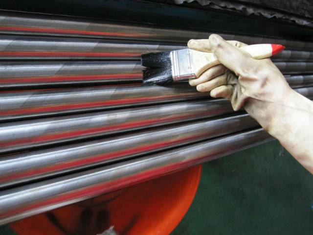 A worker is painting the anti-rust oil onto the polished rod.