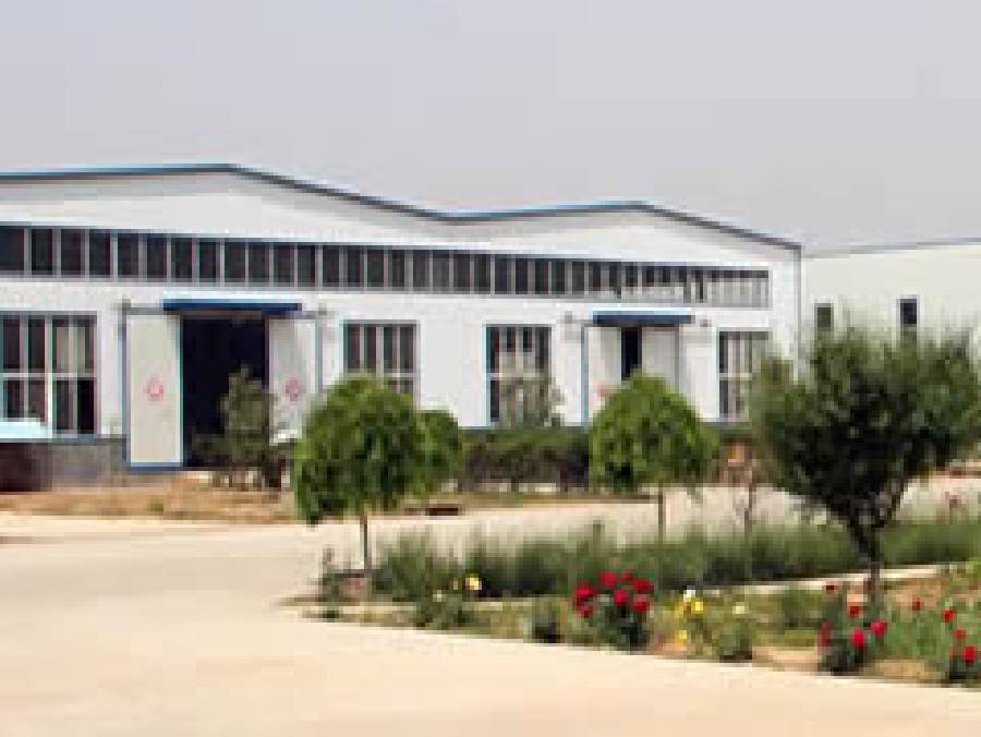 Workshop of the company and several plants and flowers beside the road.