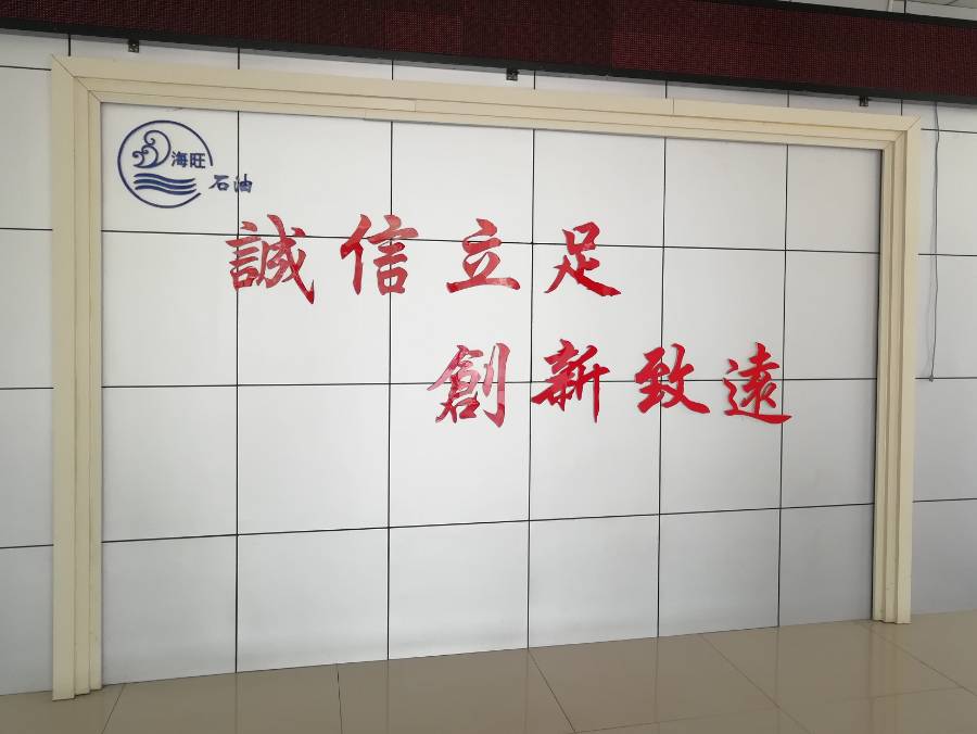 Company philosophy on the wall of the office building hall and five pots of plants on the ground.