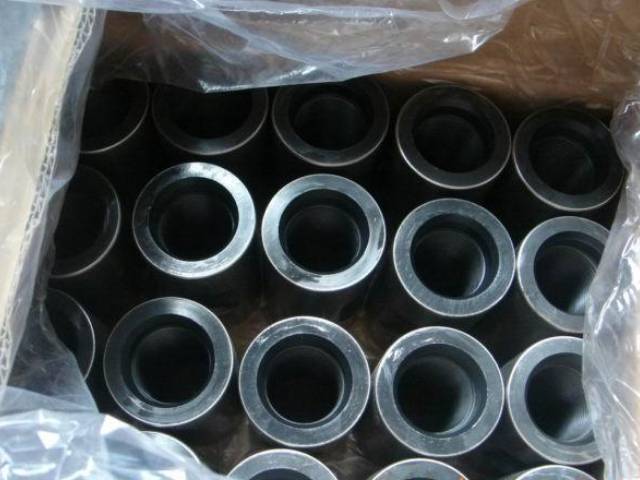 Several sucker rod couplings in the carton with plastic paper in the carton.