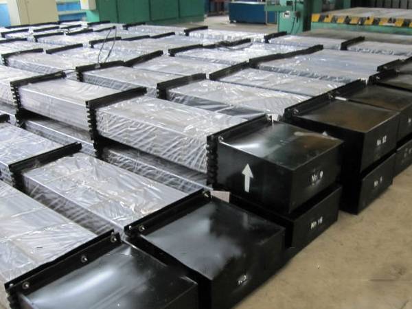 Several pallets sucker rod on the ground with plastic paper covering the rod body and metal box covering the rod head.